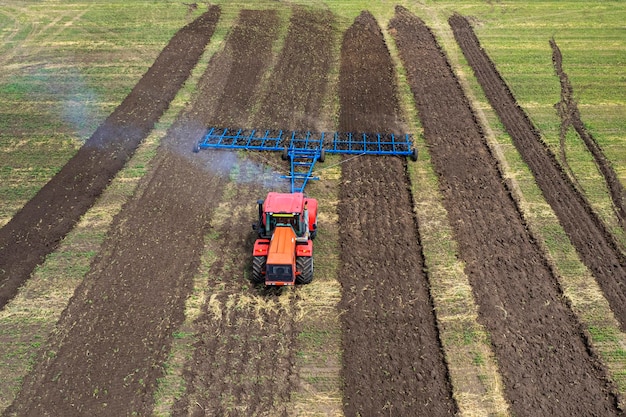 Agriculture machine harvesting crop in fields Tractor pulls a mechanism for haymaking Harvesting in autumn in morning at dawn agribusiness in the Altai region Russia aerial view from above