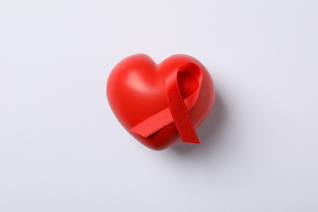 AIDS awareness red ribbon and heart on white wall, space for text