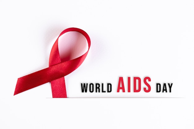 Aids Awareness Red Ribbon on white paper with text. World Aids Day concept.