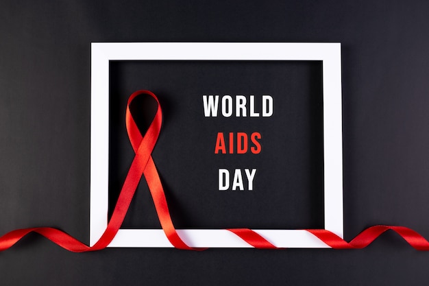 Aids awareness red ribbon wrapped white photo frame on black with text.