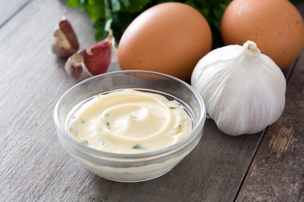 Aioli sauce and ingredients on wooden table