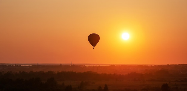 Air balloon is flying in free flight over the field Multi colored balloon in the sky at sunset