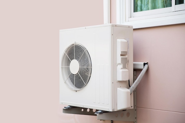 Air compressor Closeup external split wall type of outdoor home air conditioner unit installed on outside building Concepts of cool or heat or hot and air conditioning system maintenance