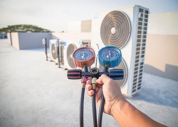 Air conditioner technician repairing central air conditioning system with outdoor tools.