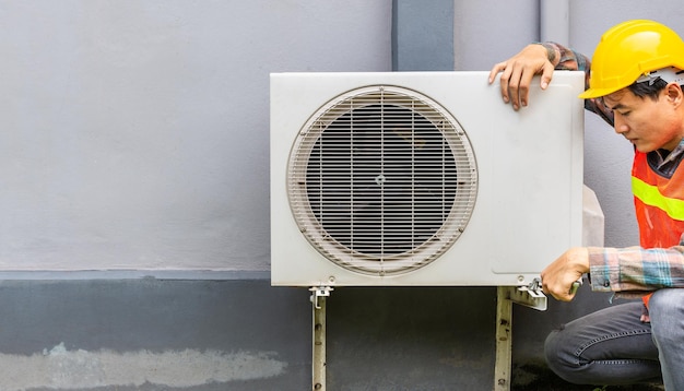 The air conditioner technician Uses a wrench to tighten the nut of the air compressor