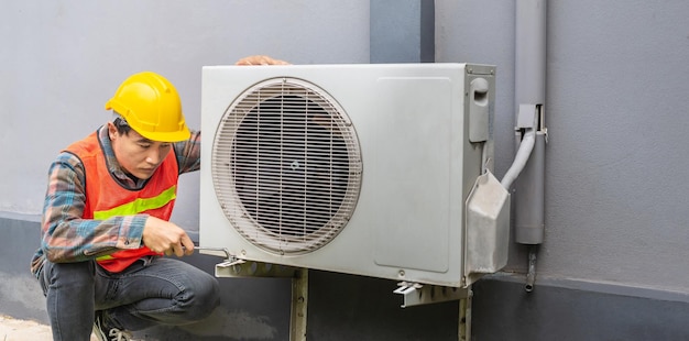 The air conditioner technician Uses a wrench to tighten the nut of the air compressor