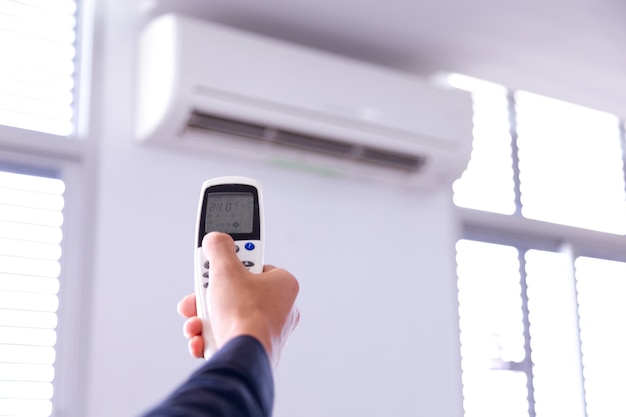 Air conditioner with remote controller,inside the room with man operating remote controller.