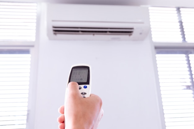 Air conditioner with remote controller,inside the room with man operating remote controller.