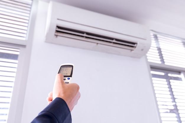 Air conditioner with remote controller,inside the room with man operating remote controller.