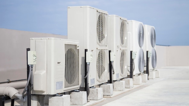 Air conditioning (HVAC) on the roof of an industrial building with blue sky and clouds.