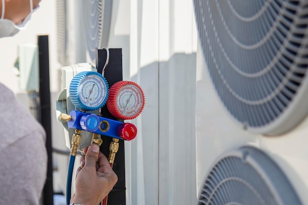 Photo air conditioning hvac service technician using gauges to check refrigerant and add refrigerant