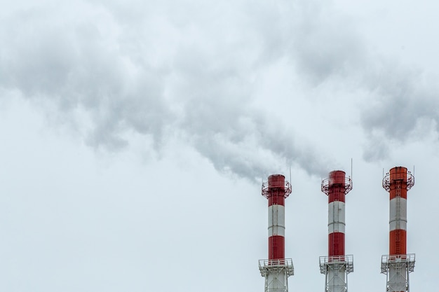 Air pollution concept. Factory smoke from pipes on a background of gray sky