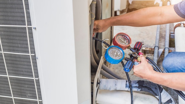 Air repair mechanic using measuring equipment for filling industrial factory air conditioners.