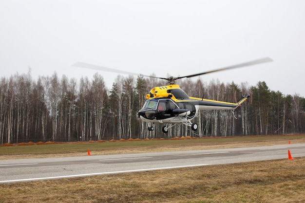 Aircraft Blackyellow helicopter makes flight at low height side view