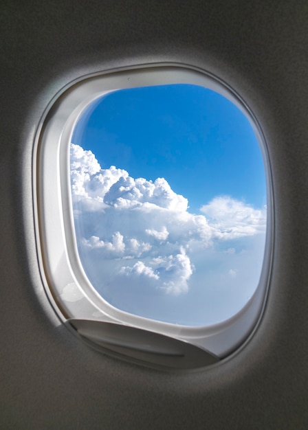 Aircraft windows frame with beautiful aerial view of clear blue cloudy sky lighted sunny beams with copyspace. Travel and transportation concept.