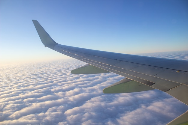 Aircraft wing in the sky at high altitude above the clouds