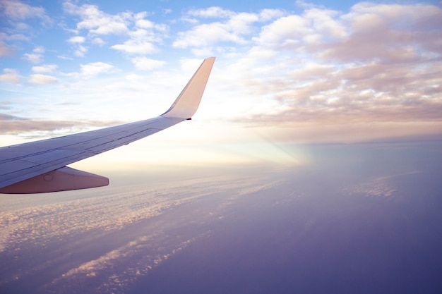 Aircraft wing view from airplane with beautiful sunset sky and clouds