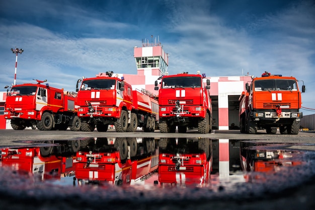 Airfield fire trucks with reflection in a puddle near garage boxes