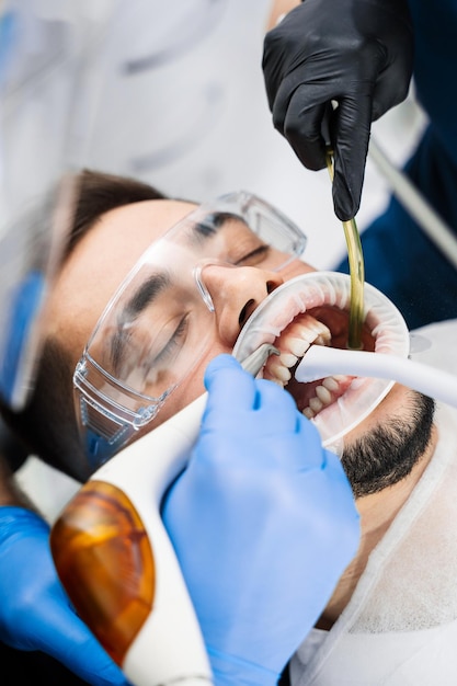 Photo airflow teeth cleaning in dental clinic assistant helps dentist to prepare teeth before treatment using airflow instrument