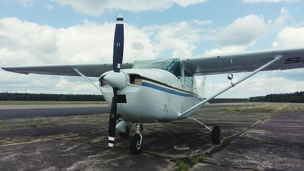 Airplane at airport runway against cloudy sky