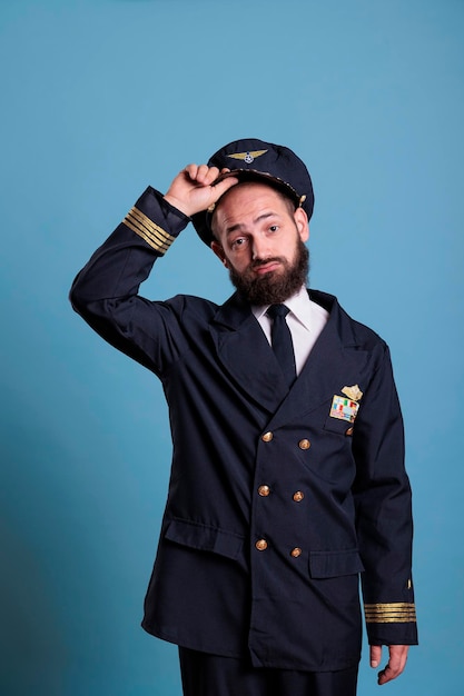 Photo airplane capitan taking hat off, looking at camera with confused facial expression. puzzled aviation academy plane pilot front view, navy aviator holding cap with airforce badge wings