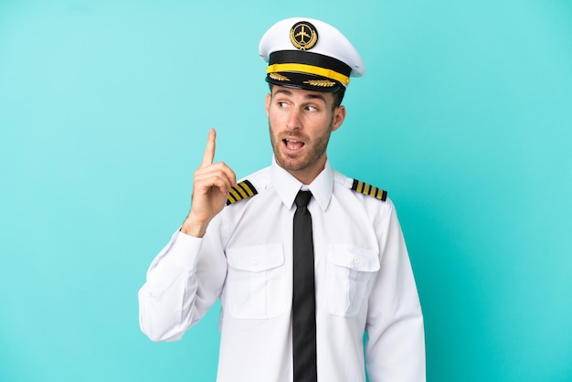 Airplane caucasian pilot isolated on blue background intending to realizes the solution while lifting a finger up