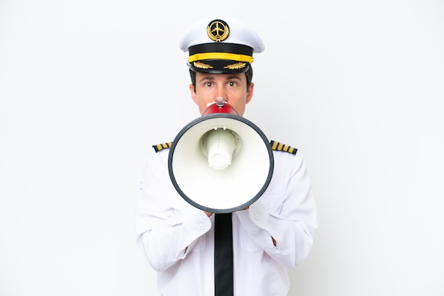 Airplane caucasian pilot isolated on white background shouting through a megaphone