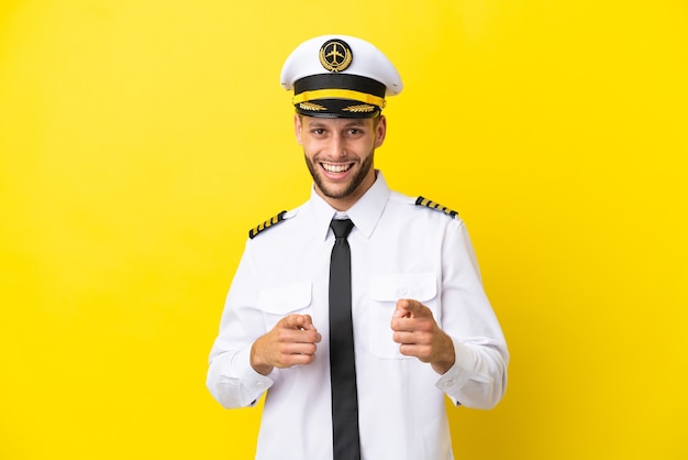 Airplane caucasian pilot isolated on yellow background pointing to the front and smiling