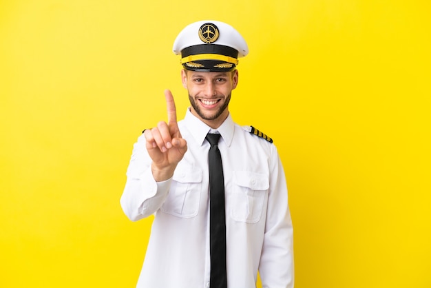 Airplane caucasian pilot isolated on yellow background showing and lifting a finger