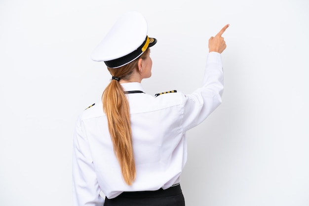 Airplane caucasian pilot woman isolated on white background pointing back with the index finger