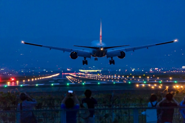 Airplane flying at airport runway against sky at night