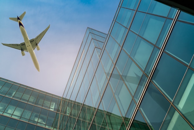 Airplane flying above office building. Skyscraper modern building. Finance business trip. Glass windows. Aviation business after coronavirus vaccine injection. Plane flying above futuristic building.