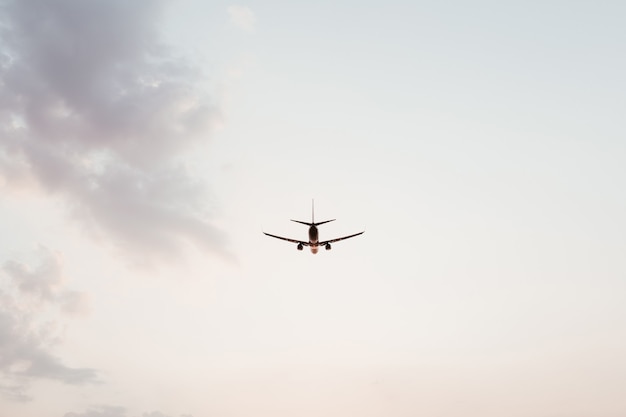 Airplane flying in the sky at sunset with pink purple clouds