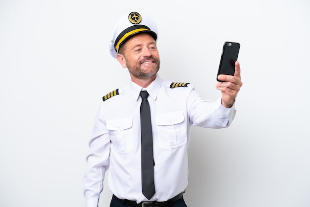 Airplane middle age pilot isolated on white background making a selfie