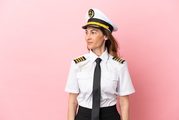 Airplane middle aged pilot woman isolated on pink background looking side