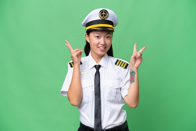 Airplane pilot Asian woman over isolated background showing victory sign with both hands