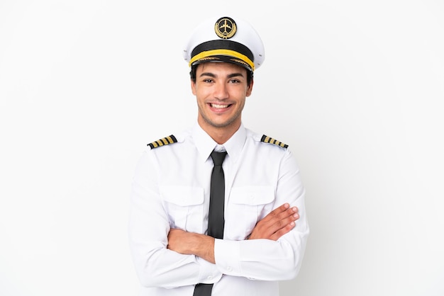 Airplane pilot over isolated white background keeping the arms crossed in frontal position