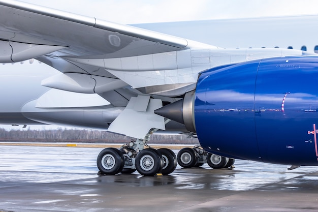 Airplane side view at the airport showing landing gear, under wing and engine.