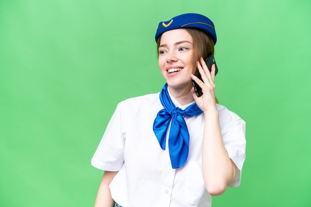 Airplane stewardess over isolated chroma key background keeping a conversation with the mobile phone