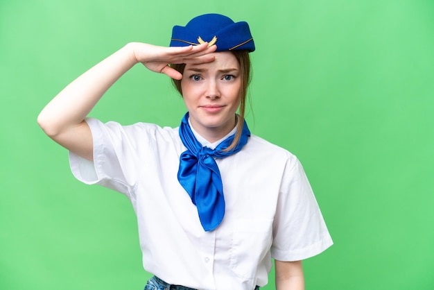 Airplane stewardess over isolated chroma key background looking far away with hand to look something