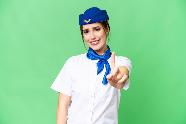 Airplane stewardess over isolated chroma key background showing and lifting a finger