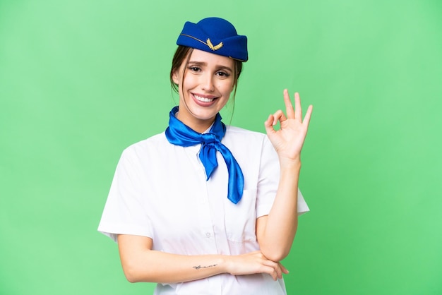 Airplane stewardess over isolated chroma key background showing ok sign with fingers