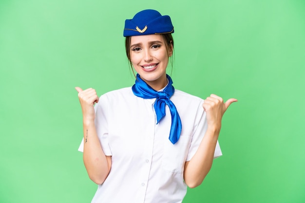 Airplane stewardess over isolated chroma key background with thumbs up gesture and smiling