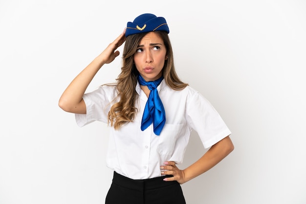 Airplane stewardess over isolated white background having doubts and with confuse face expression