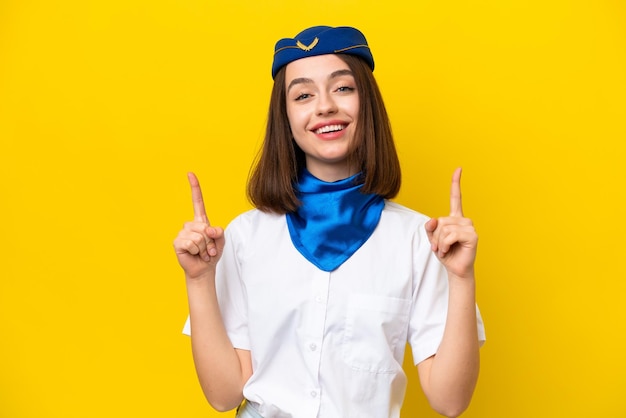 Airplane stewardess Ukrainian woman isolated on yellow background pointing up a great idea