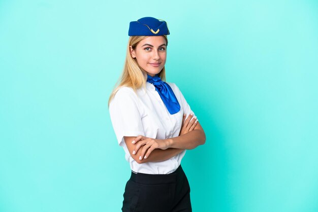 Airplane stewardess Uruguayan woman isolated on blue background with arms crossed and looking forward