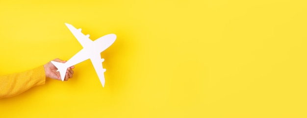 Photo airplane symbol in hand over yellow background, panoramic layout