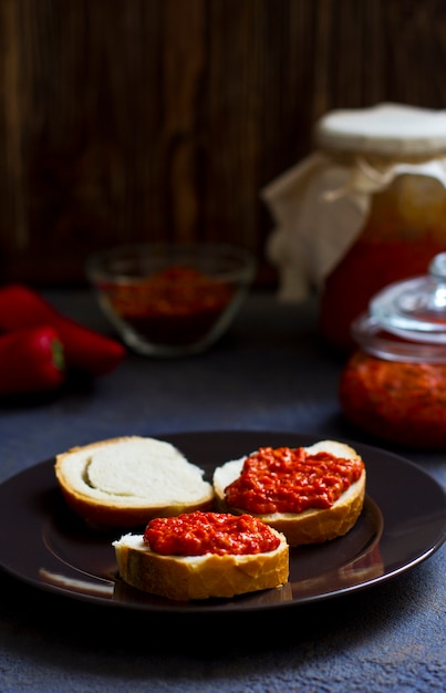 Ajvar, appetizer of baked peppers on the table, bread with ajvar, toast with ajvar, balkan appetizer of baked peppers, vertical, space for your text