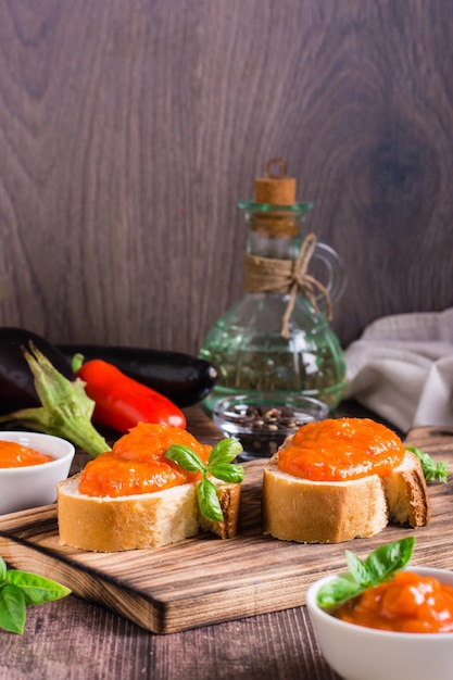 Ajvar delicious appetizer of pepper eggplant and garlic on bread and in bowls Vertical view