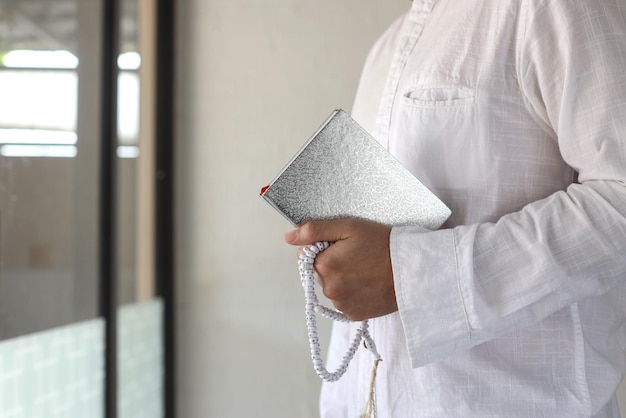 Al Quran and tasbih as muslim prayer beads holded by muslim man at the mosque. Islamic Background.